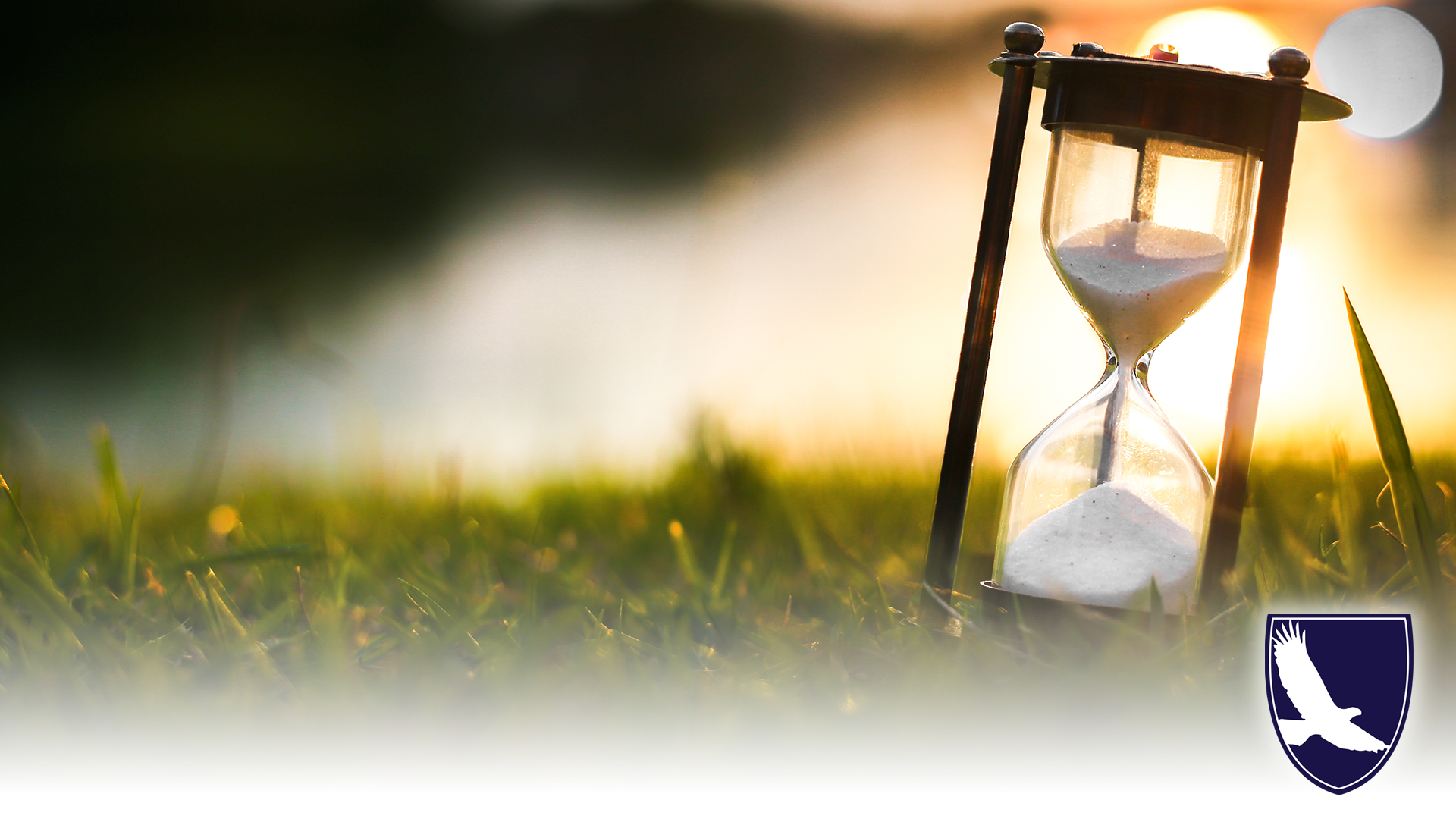 grass field with hourglass on right side. hourglass sand is half-complete